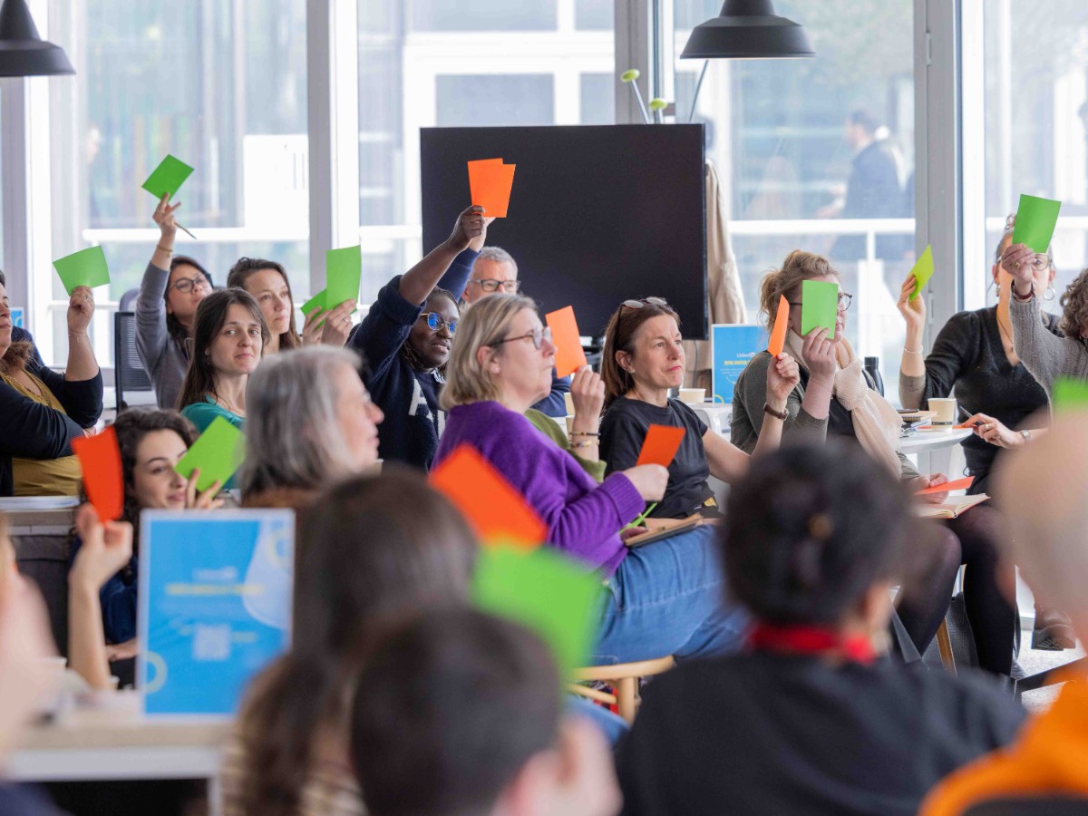 Des participants lèvent des cartons verts et orange pour se prononcer sur les propositions