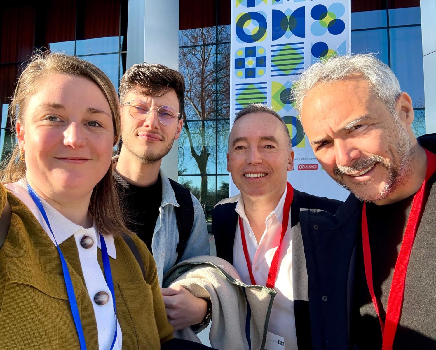 Quatre membres de l’équipe devant un lieu de conférence